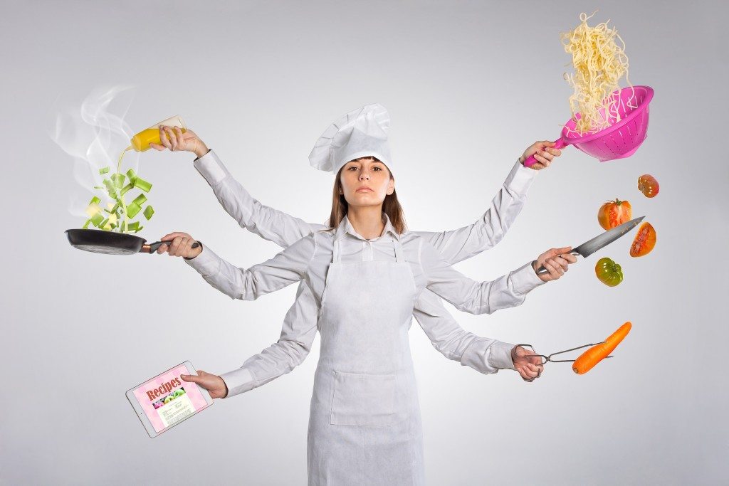 Superwoman preparing food, cooking and looking recipes at the same time