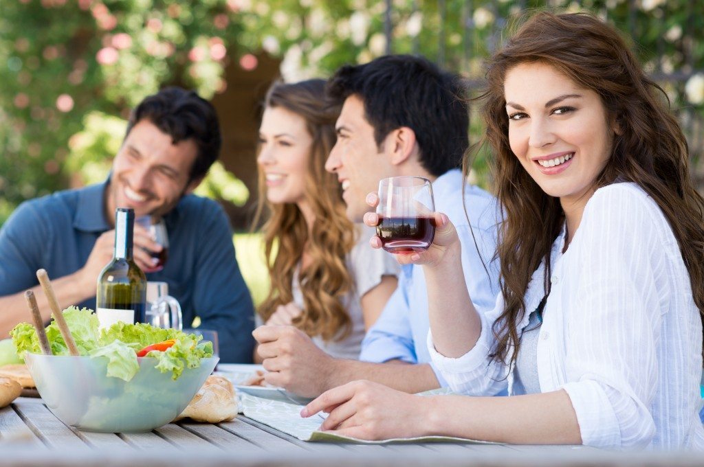 Happy Woman Holding Glass Of Wine With His Friends In Background