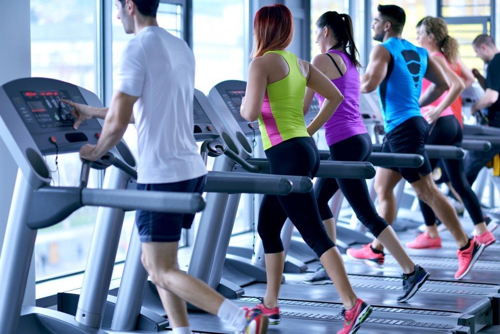 group of young people running on treadmills in modern sport gym