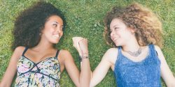 Two beautiful women lying on the grass. One is caucasian, the other is black, multicultural and friendship concepts.