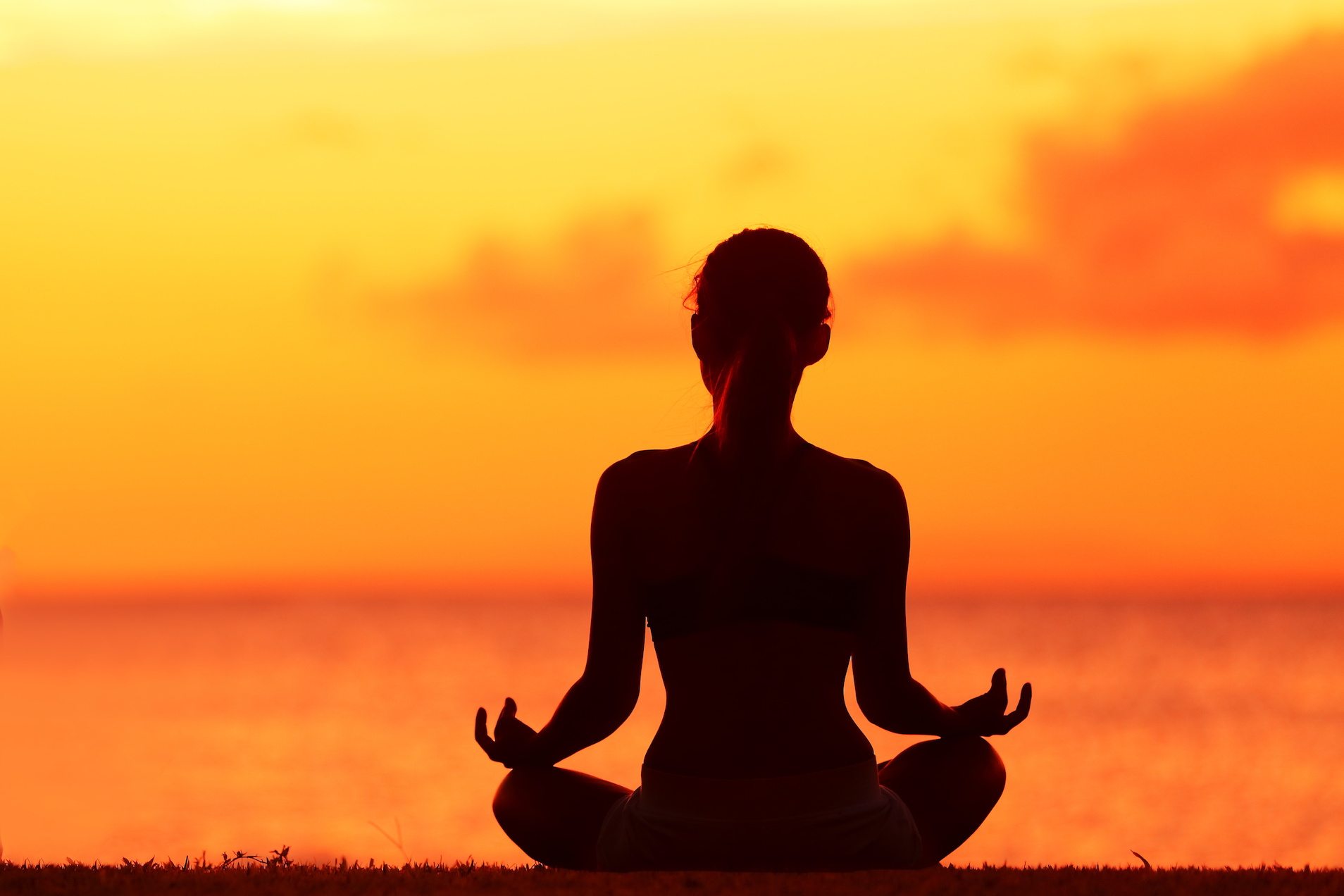 Wellness woman doing zen yoga meditation on beach