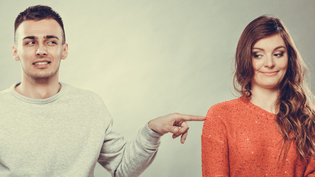 Shy woman and man sitting on sofa couch next each other. First date. Attractive girl and handsome guy meeting dating and trying to talk. Male touching picking up female. Instagram filtered.